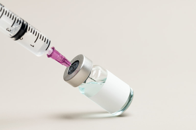 Close-up of a blank glass injection vial with a clear liquid inside, isolated on a white background. Botox aftercare recommendations from professionals.